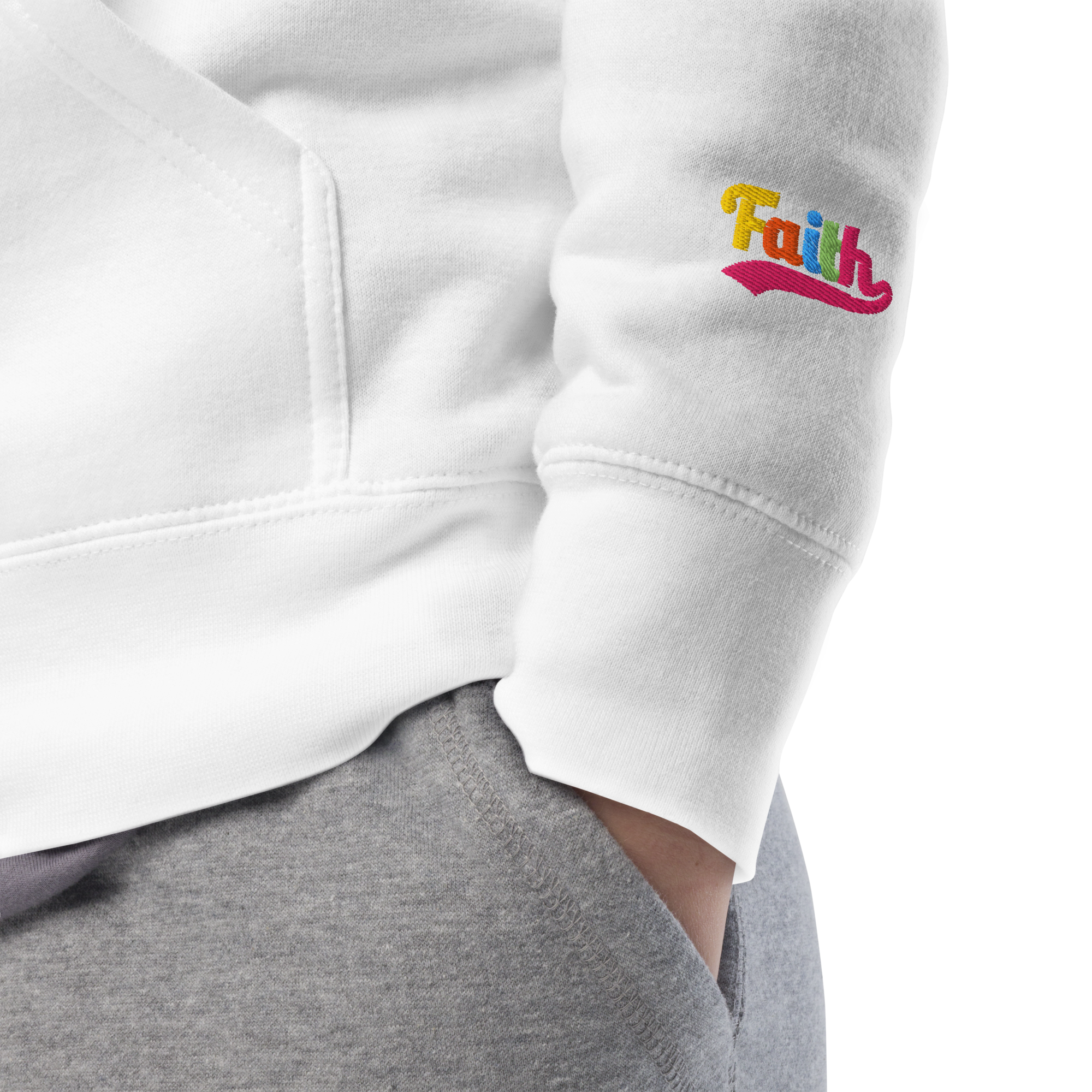 White sweatshirt with 'Faith' embroidered on the sleeve, worn by a person.